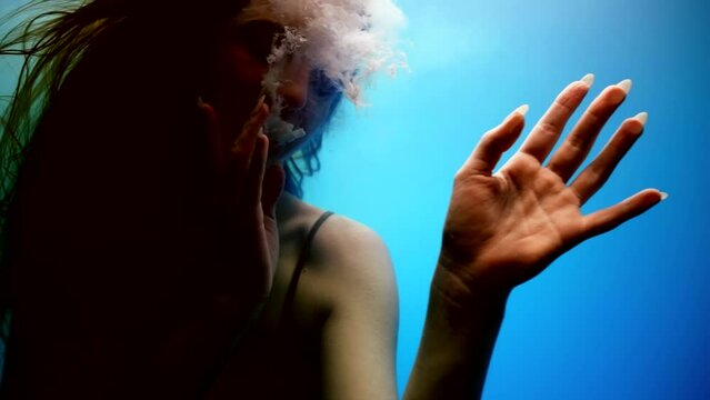 mysterious underwater shot with beautiful young woman possessed by demon, exhaling grey smoke