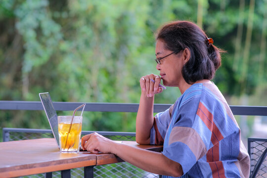 Side view: A middle-aged woman is working on her laptop in an open space