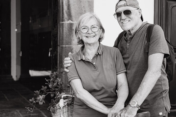 Black and white portrait of cheerful senior couple looking at camera smiling sitting outdoors on the bicycle enjoying active lifestyle