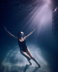 Fototapeta na wymiar A girl in a mask underwater in the pool in the water