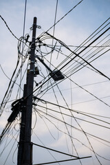 Messy electricity wires on the street against blue sky background