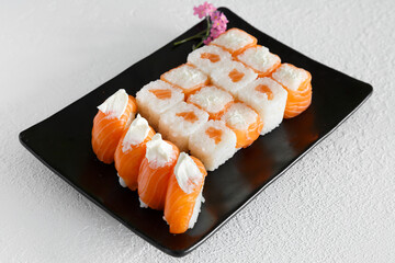 Assortiment de sushi et california rolls sur une assiette noir et fond blanc. Cuisine japonaise.