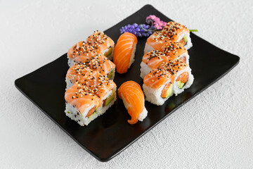 Assortiment de sushi et california rolls sur une assiette noir et fond blanc. Cuisine japonaise.