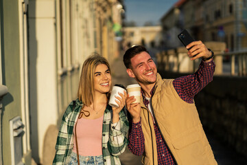 tourists are taking photos using smart phone, holding a to go coffee in hand