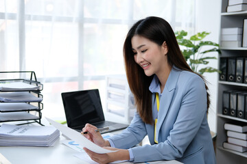 Asian businesswoman analyzing reports while working in office.