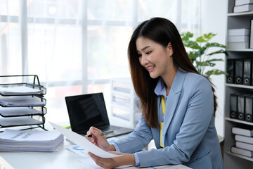 Asian businesswoman analyzing reports while working in office.