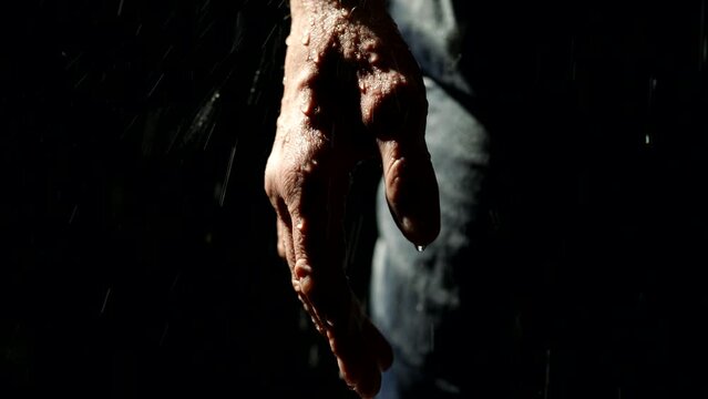 lonely man in rain in night, close up view of male hand with raindrops, maniac or victim