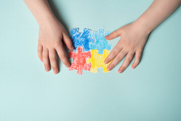 Children's hands laying out a colored puzzle, symbol of World Autism Awareness Day. Copy space