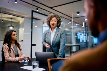 Female CEO holding business meeting with younger colleagues in office.
