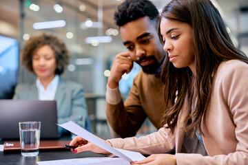Young black couple analyzing paperwork during meeting with bank manager in office.