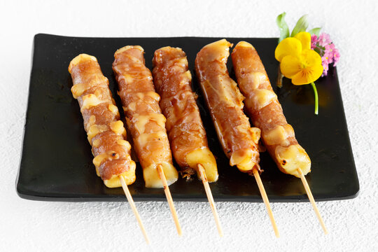 Assortiment de brochettes yakitori: brochette de poulet, brochette de boeuf fromage, brochette de saumon sur une assiette noir et fond blanc. Cuisine japonaise.