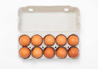 Brown raw fresh eggs in paper tray on white background.