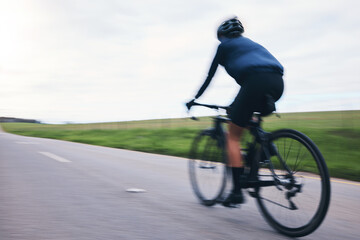 Person, bicycle and cycling on motion blur, sky mockup and countryside road for triathlon from behind. Cyclist, bike and speed for sports training, cardio performance and power for competition race