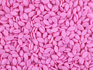 Beautiful granules of pink wax for depilation face arеa top view. Epilation, depilation, unwanted hair removal. Natural depilatory wax bean granules. Texture background.