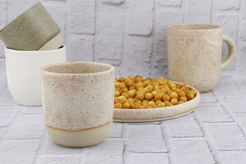 Ceramic cups in different sizes and colors. set of glasses and plates from ceramics on a gray background. Earthenware covered with matte glaze. Ceramic handmade