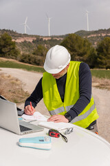 wind turbine or windmill technician engineer working and consulting a blueprint of a sustainable, clean and green energy wind farm
