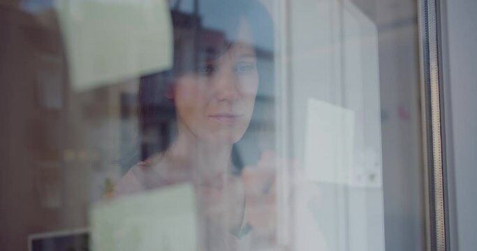Young businesswoman working with stickers note on glass window