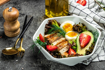 Healthy nutritious paleo keto breakfast diet two eggs, avocado, grilled chicken fillet, nuts, strawberries and fresh salad. Keto breakfast or lunch. place for text, top view