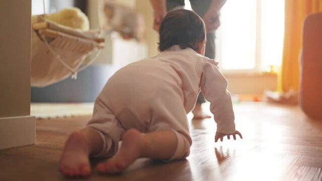 father teaches baby to crawl. happy family a first steps kid dream concept. father helps baby newborn crawling on the floor in house. baby girl crawling on the floor takes her first lifestyle steps