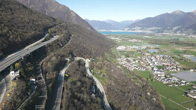 Aerial View of Highway and Railroad Above Valley and Small Town by Lake in Swiss Alps on Sunny Spring Day