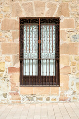 Fototapeta na wymiar window in stone wall with decorative wrought iron fence