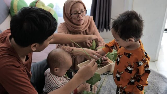 Indonesian Muslim family making ketupat together in the family room during Eid al-Fitr - Top shot