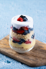 Trifle dessert with berries and cream on blue background