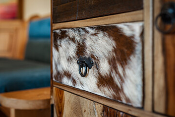 Detailed view of a cupboard with drawers in the kitchen. One drawer element is covered with cowhide.