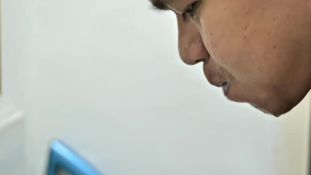 Man gargles at the sink in front of the mirror