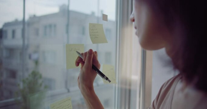 Business woman working in home write on sticker on window glass