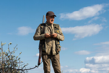 Mature man hunter with gun while walking on field.