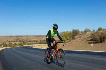 Obraz premium Cyclist riding bicycle on road against clear sky
