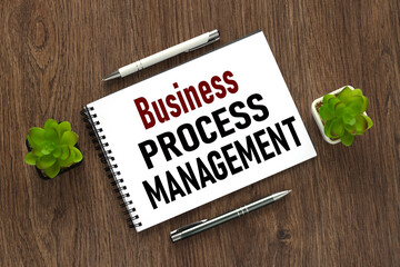 BPM concept: business process management . top view of notepad with spring. text on notepad near potted plants