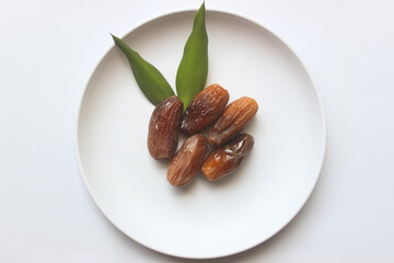 Dried dates on a white plate for Ramadan on a white background