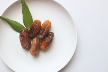 Dried dates on a white plate for Ramadan on a white background