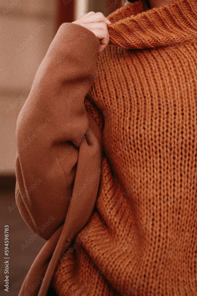 Sticker details of orange warm cozy female sweater and brown coat. outdoor portrait. autumn winter street st