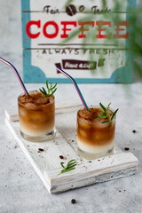 Ice coffee in a transparent glass. Iced coffee served in glass with coffee cubes and milk on a wooden tray.
