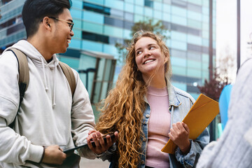 Exchange university students talking in urban campus - Teenager Asian boy and blond girl friends