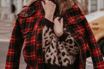 Female body in a red plaid jacket and fluffy leopard sweater. Street style casual fashion details