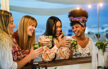 Multiracial happy friends cheering and drinking mojitos at beach party - Focus on center african...