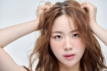 Fototapeta premium Beautiful Young Asian woman with clean fresh skin touching two hands on face in beauty pose. Pretty girl smiling in white background. Facial treatment, cosmetology, cosmetic surgery, make up concept.