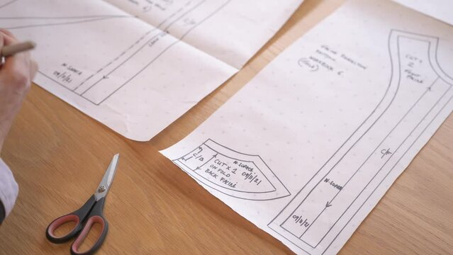 Static shot of a fashion designer drawing and blueprinting plans to manufacture a piece of clothing. Shot in a fashion workshop in Stornoway on the Isle of Lewis, part of the Hebrides of Scotland.