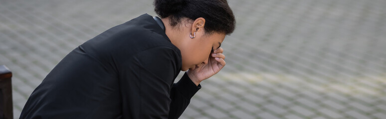 Fototapeta premium Side view of young multiracial woman with depression looking down on urban street, banner.