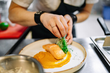 Chef cooking Roasted salmon steak with pumpkin cream on restaurant kitchen