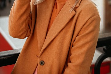 Fashion details of orange knitted cozy sweater and brown autumn coat. Mid season casual fashion...