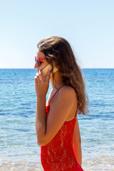 young smiling woman talking by phone on a beach