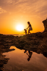 Silhouette of mother and son walking in the sunset on the beach of Tacoron in El Hierro, Canary Islands, vacation concept, orange sunset, walking by the sea
