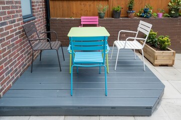 Newly built and painted gray with colorful furniture wooden deck in back garden.