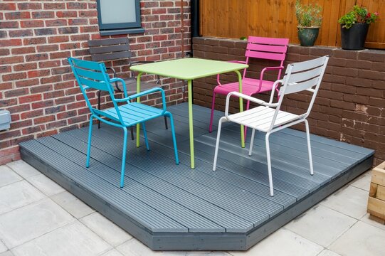 Newly built and painted gray with colorful furniture wooden deck in back garden.