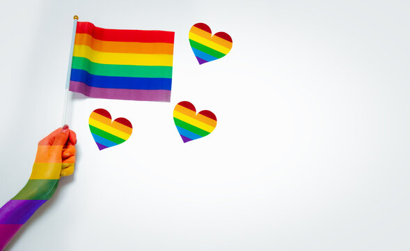 gay pride month and lgbtq festival concept. a hand holding pride flags with rainboe hearts on white background	